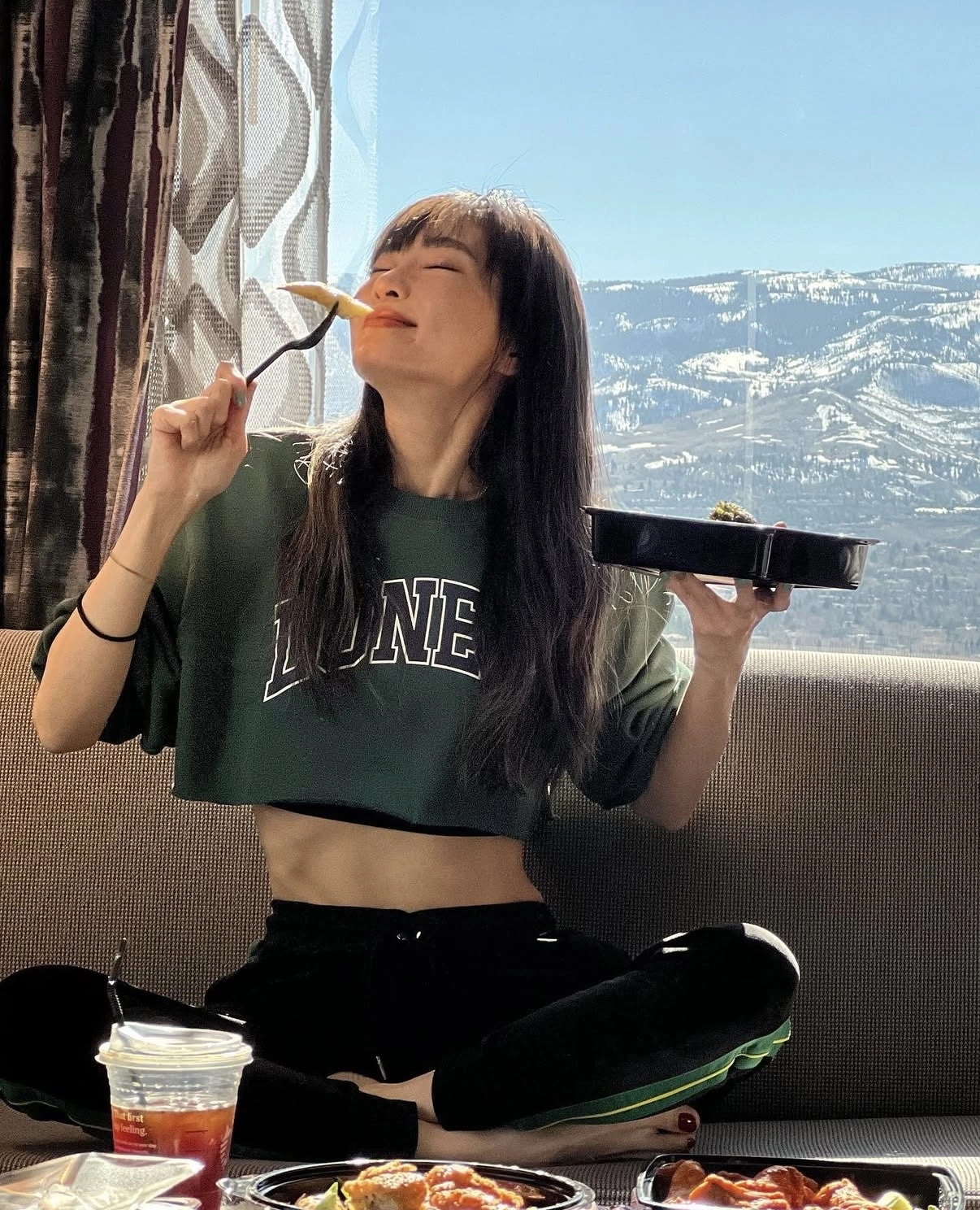 謝金燕坐在室內窗邊用餐，展現自律飲食與輕盈體態形象